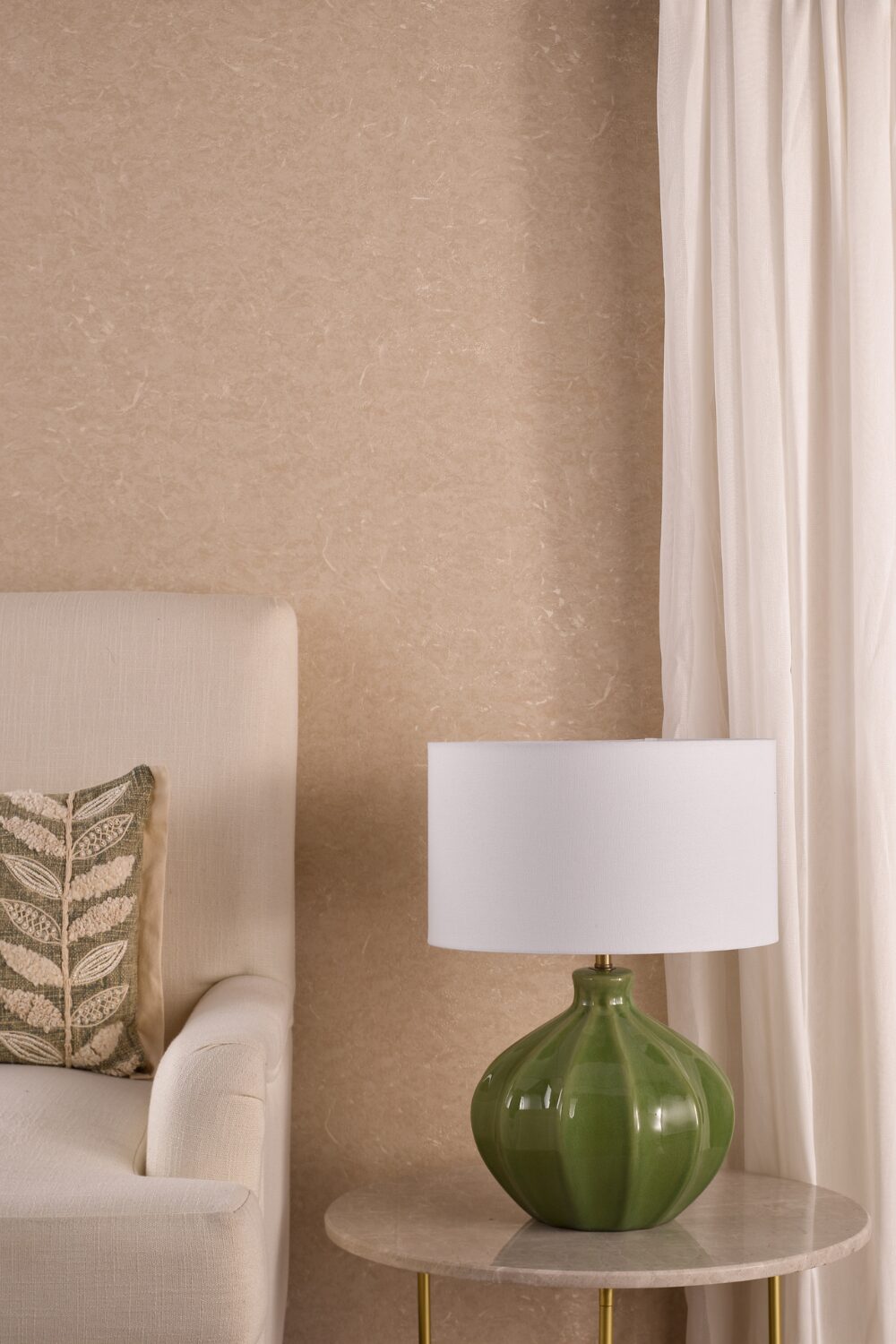 White armchair next to circular table holding green lamp