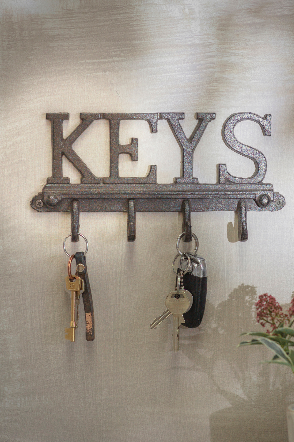Metal key holder on white wall with two sets of keys hanging from hooks