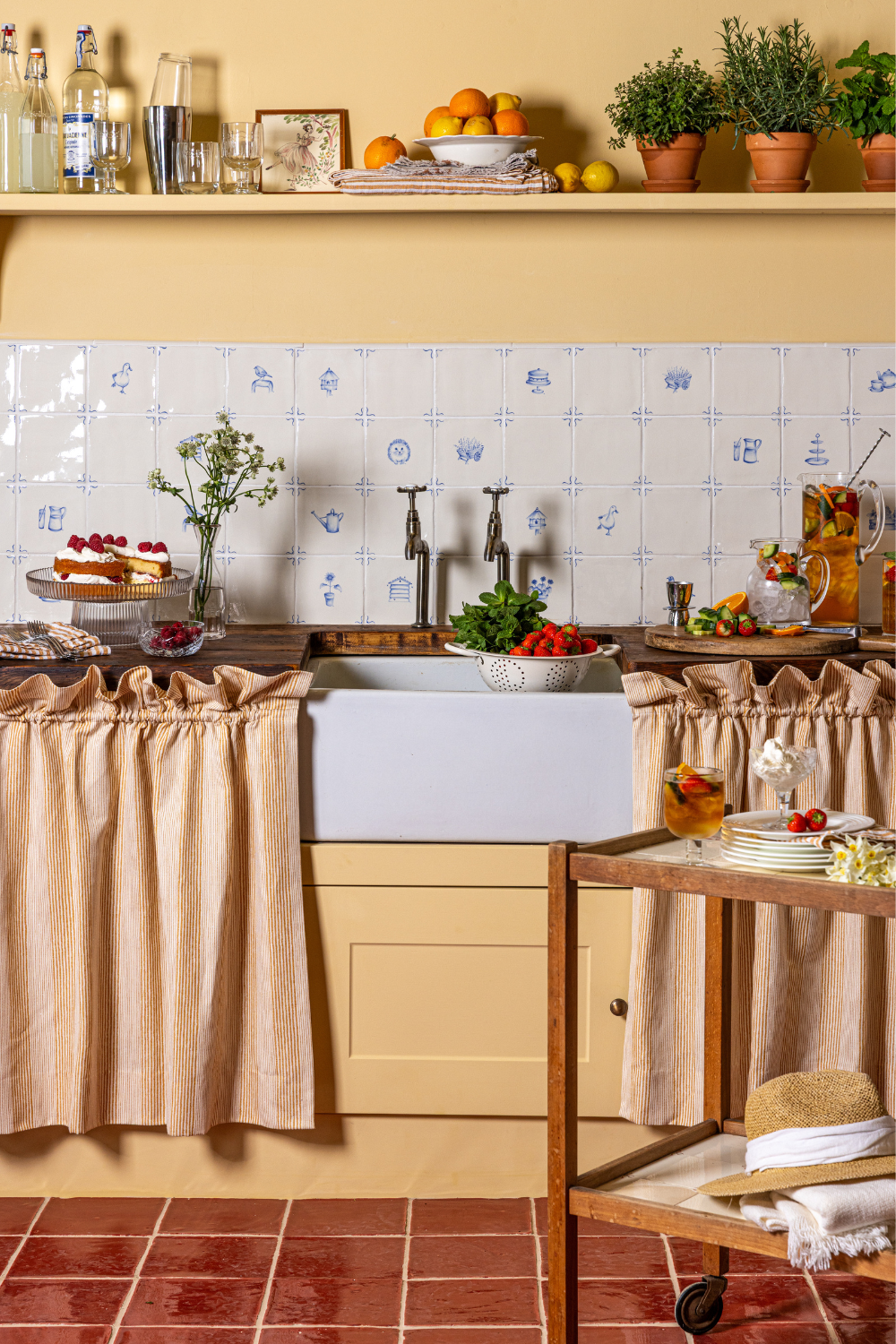 Yellow kitchen with wooden counters, wooden drinks trolley and striped sink skirt