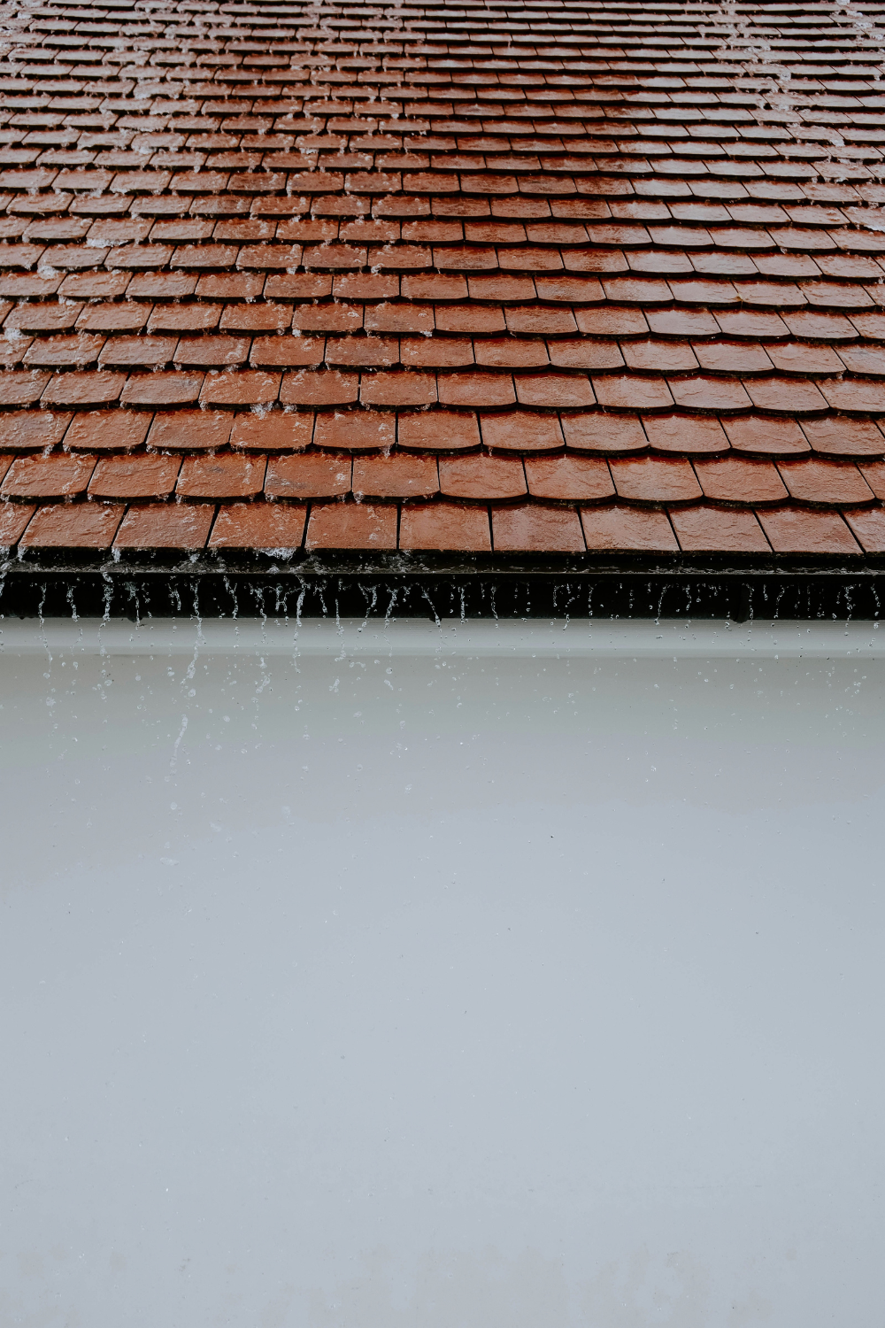 Rainwater cascading down a red tile roof