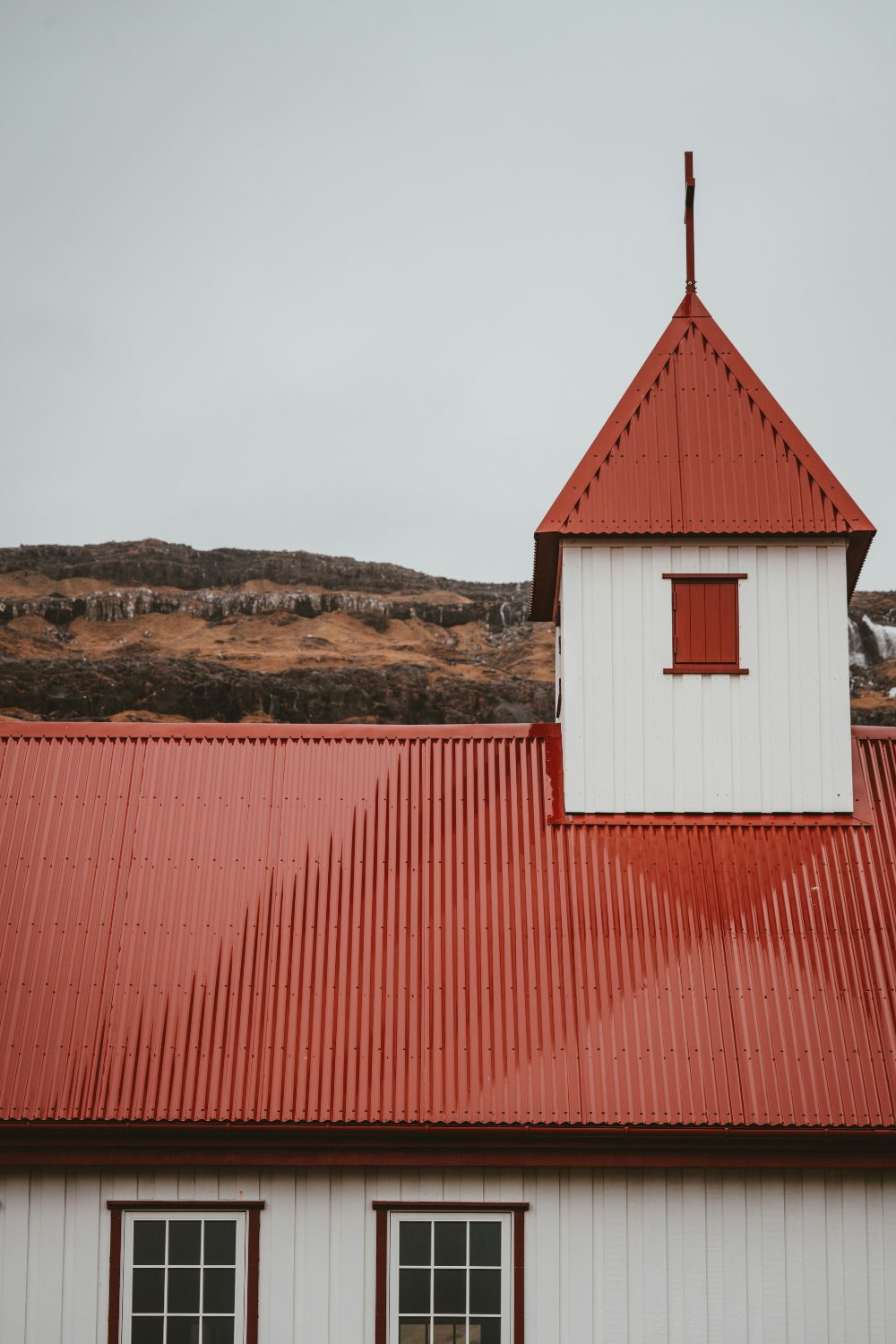 White church with red metal roof and square metallic steeple