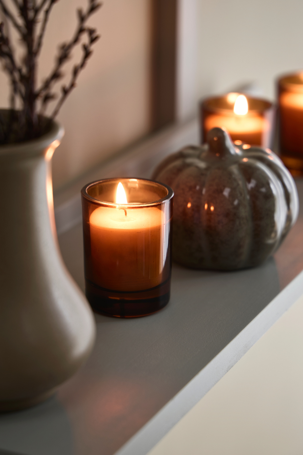 Jar candles, white vase and decorative pumpkin on white mantelpiece