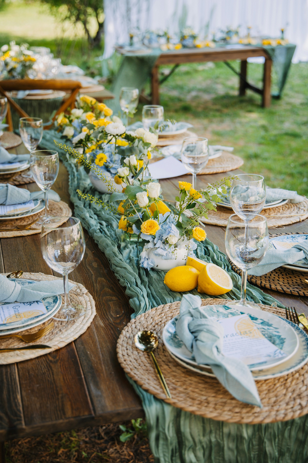 Wooden tables set with green tablecloth, lemons and yellow flowers