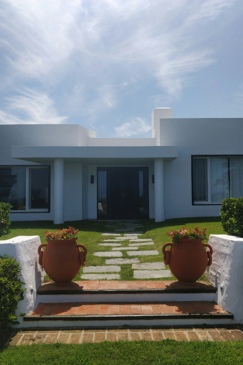 Modern white house and garden with stepping stone path, brick steps and terracotta planters