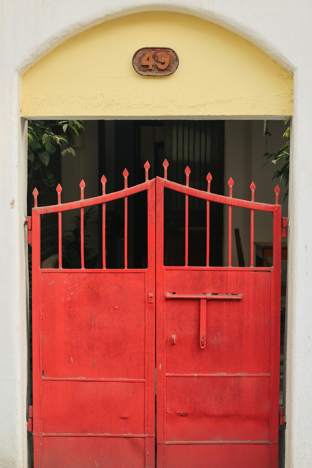 Red metal gate with spiked top in white archway